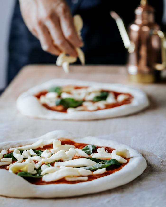 about-04 A close-up of a hand preparing Neapolitan pizza with fresh toppings in a London kitchen.